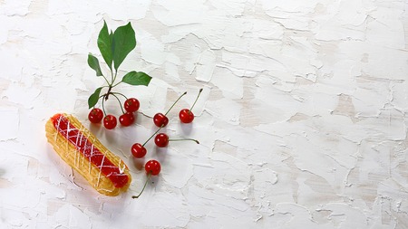 Homemade french eclairs with white icing and cherry jam, fresh cherries. Summer fruit dessert. Top...