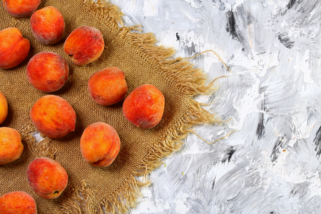 A group of ripe peaches on the old fabric. light background. Fresh peach concept. Flat lay. Copy text.の写真素材