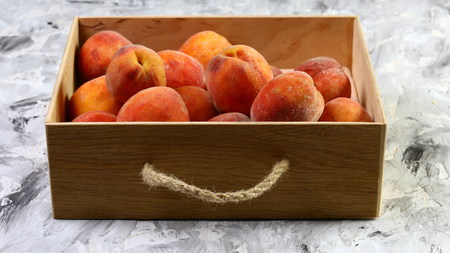 freshly harvested peaches in a wooden crate. On the black table. Free space for text. Top view.の写真素材