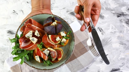 plate of sandwiches in the hands of the chief cook with figs, blue cheese and prosciutto. Flat lay, Copy space.の写真素材