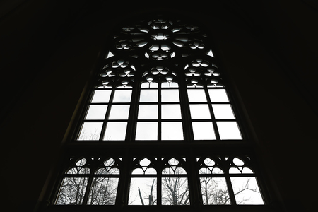 inverted silhouette of large medieval window in backlight in Gothic style.