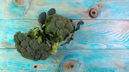 Fresh green broccoli in wood bowl over rustic wooden background - healthy or vegetarian food concept. Authentic lifestyle image. Top view.の写真素材