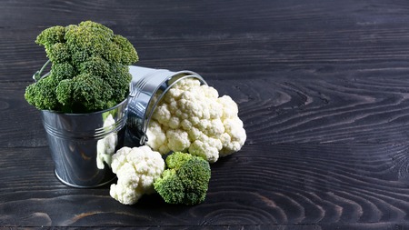 Assortment of cabbages green broccoli in metal buckets on a black wooden background. Authentic lifestyle image. Top view with copy space.の写真素材