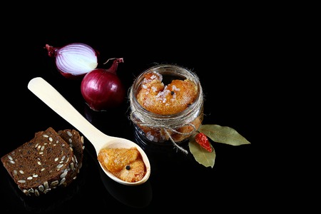 Gourmet food Pike caviar, roe in a glass jar, red hot pepper, laurel leaves, wooden spoon of fish caviar on a black background, Flat lay. Copy space.の写真素材