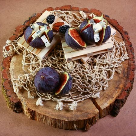 Gourmet appetizer of figs with dorblyu cheese, walnuts and honey on wooden stump, traditional Turkish dessert, Seasonal harvest crop local produce concept. top view.の写真素材