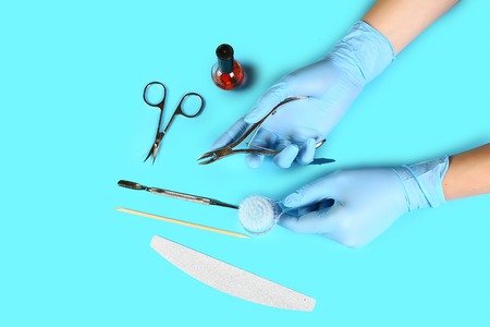 set of manicure accessories on blue background top view. flat lay Manicure tool in the hands of the master. the concept of safe manicure.の写真素材