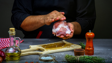 Cooking meat steak, vegetables and spices with by chef hands on wooden background. cooking recipe.の写真素材