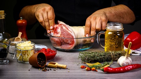 Raw pork knuckle by chef hands, Aromatic spices, and a glass of beer, sauerkraut. Ready to bake.の写真素材