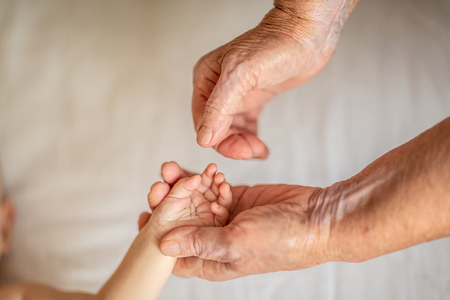 old and newborn hands touching each other. Beautiful conceptual image of a new generation.の写真素材
