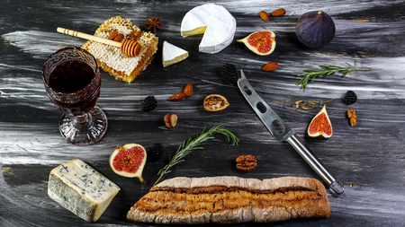 Red and white wine plus different kinds of cheeses cheeseboard on rustic wooden table. French food tasting party or feast scenery from above top view.の写真素材