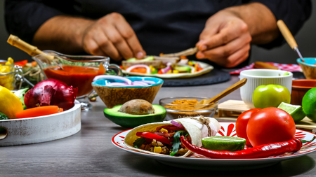 Close up of a chef hands preparing Taco. Cook preparing delicious Taco at kitchen. The concept of mexican cooking recipe.の写真素材