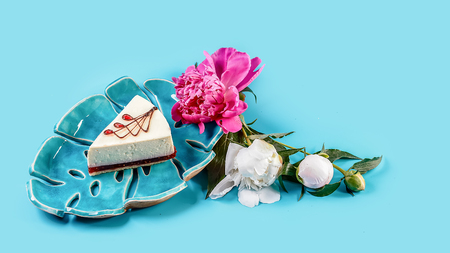 Piece of cheesecake with raspberries and spring flowers jasmine isolated on blue background.の写真素材