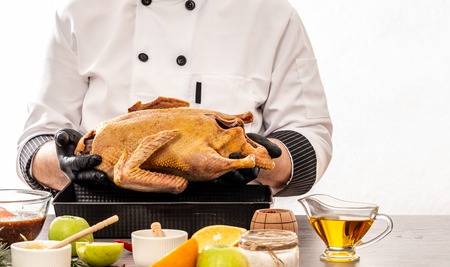concept of chinese cuisine. Cooking baked duck by cook hands, cooking ingredients on kitchen table white background. copy text.の写真素材