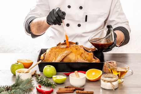 Close up of a chef hands preparing duck with soy sauce, oranges and apples on frying pan. The concept cooking recipe.の写真素材