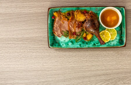 delicious cooked duck legs served with orange sauce on blue plate, menu in an Italian restaurant. top view. place for text.の写真素材