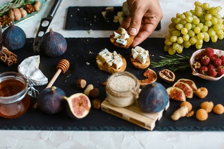 Chef hands cooking bruschetta of cheese, figs and honey. sprinkle with sesame seeds. Raw ingredients for cooking healthy snacks, good for diet, clean eating.の写真素材