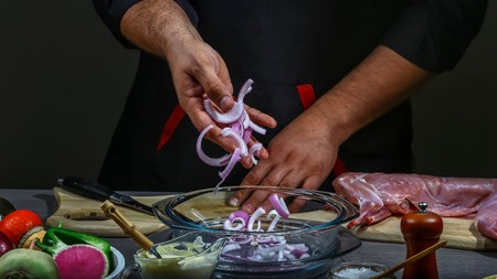 cook's hand with onion. rabbit with sour cream sauce. Food concept.の写真素材