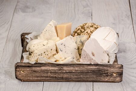 various types of cheese in wooden box on white wooden table.の写真素材