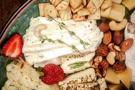 Cheese plate served with blueberry, strawberry, crackers and nuts, Top view. Assorted cheeses Camembert, Brie, Parmesan blue cheese, goat.の写真素材