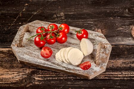 Mozzarella cheese, basil and tomato cherry on slate stone board, copy space. Ingredients for Caprese...