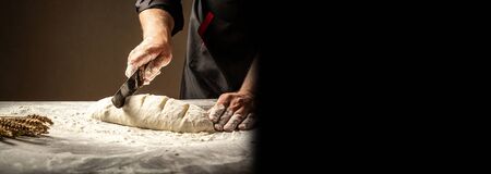 Baker making patterns on raw bread using a knife to shape the dough prior to baking. Manufacturing process of spanish bread. Food concept.の写真素材