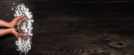 Girl's hands in the shape of a heart with flour on dark black table, Food recipe menu background. place for text. Long banner format.の写真素材