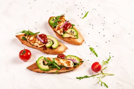 Sandwich grilled halumi cheese and slices of avocado on a light background. Healthy vegetarian food. Top view, overhead, banner.の写真素材