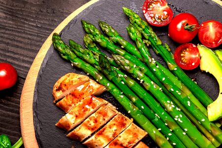 Baked chicken garnished with asparagus and herbs. Healthy food, ketogenic diet, diet lunch concept. Keto Paleo diet menu. Top view, overhead.の写真素材