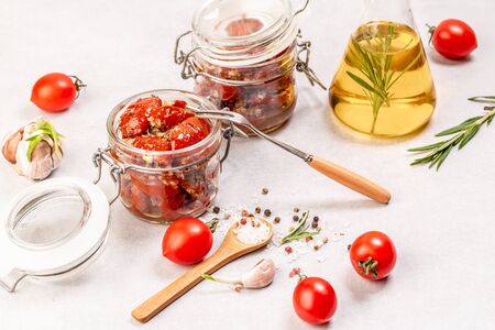 Sun dried tomatoes with fresh herbs and spices in olive oil in a glass jar Food recipe background. space for text. top view.の写真素材