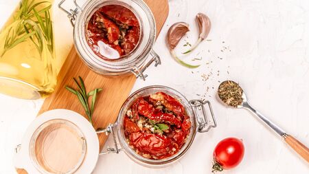 tomato dried tomatoes, dried tomatoes in jar, basil, and herbs in spoon on a light table. top view. Long banner format. space for text.の写真素材