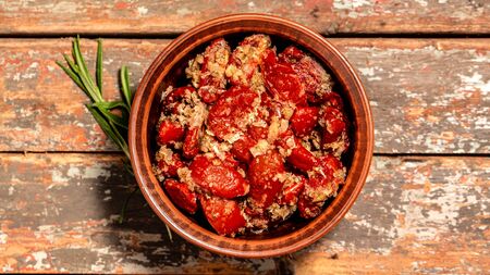 Sun dried tomatoes with fresh herbs and spices. Bowl of sun dried tomatoes garlic, oregano, olive oil on wooden background, top view.の写真素材
