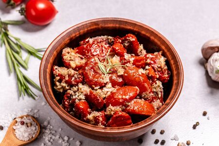 Sun-dried tomatoes with garlic, oregano, olive oil in bowl on a light table, top view.の写真素材