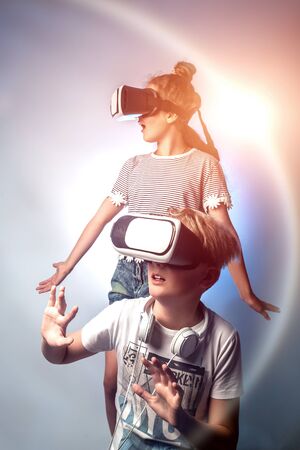 Smartphone apps icons against school boy and girl in virtual reality glasses. The concept of modern technologies of the future.の写真素材