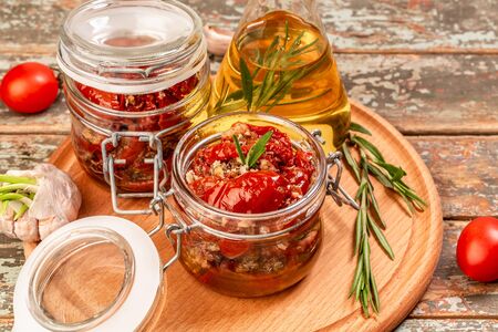 Sun dried tomatoes with fresh herbs and spices, olive oil in a glass jar. banner format.の写真素材