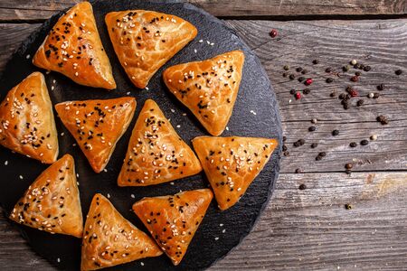 Slate plate with delicious samosas on rustic background, top view.