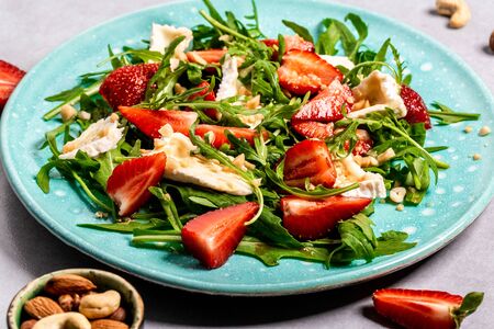 Fresh salad with arugula, strawberries and cheese brie, camembert. Healthy organic diet food concept. Food recipe background. Close up.の写真素材
