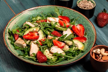 Plate with a keto diet food. strawberry salad with arugula, chicken, avocado and strawberries. Food recipe background. Close up.の写真素材