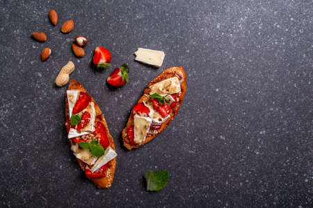 Crostini with strawberries, cheese camembert, nuts and honey. top viewの写真素材