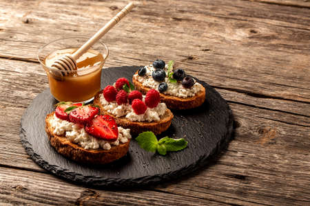 Bruschetta or toast with goat cheese, berries and honey. Food recipe background. Close up top view.の写真素材