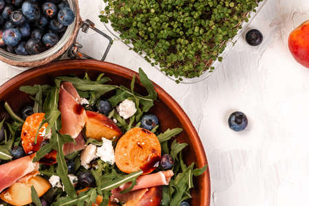 Delicious salad with grilled peaches, prosciutto and cheese, snack on a light background, top view.の写真素材