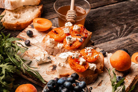 Vegan food. snack sandwiches with grilled peaches, dor blue cheese, blueberries and honey, wooden...