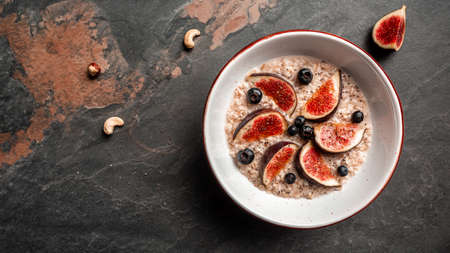 Delicious and healthy oatmeal with figs, blueberries and chia seeds on a dark background. Gluten free, lactose free, top view.の写真素材
