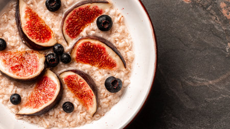 Healthy breakfast. Bowl of oatmeal, figs, chia seeds, and nuts, fresh blueberries, top view horizontal.の写真素材