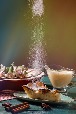 Cheesecake apples with apples and cinnamon spices, Powdered sugar is poured out of a sieve on a cheesecake.の写真素材