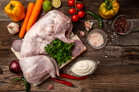 Fresh raw rabbit on a wooden table with vegetables and spices, Food recipe background. space for text. top viewの写真素材