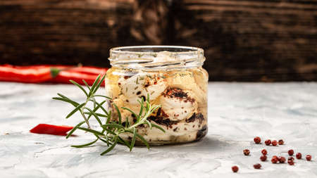 Jar with cheese marinated in oil on white wooden table. Ecology and eco-products, tasty and healthy...