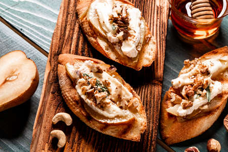 Appetizers table with italian antipasti snack. Pear and brie crostini with honey, pecan and rosemaryの写真素材