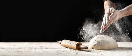 White flour flying into air as pastry chef in white suit slams ball dough on white powder covered table. concept of nature, Italy, food, diet and bioの写真素材