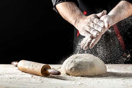 Photo of flour and men hands with flour splash. Cooking bread. Kneading the Dough.の写真素材