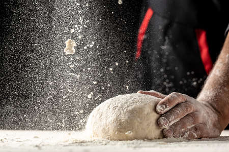Photo of flour and men hands with flour splash, ball dough on white powder covered table. concept of nature, Italy, food, diet and bioの写真素材
